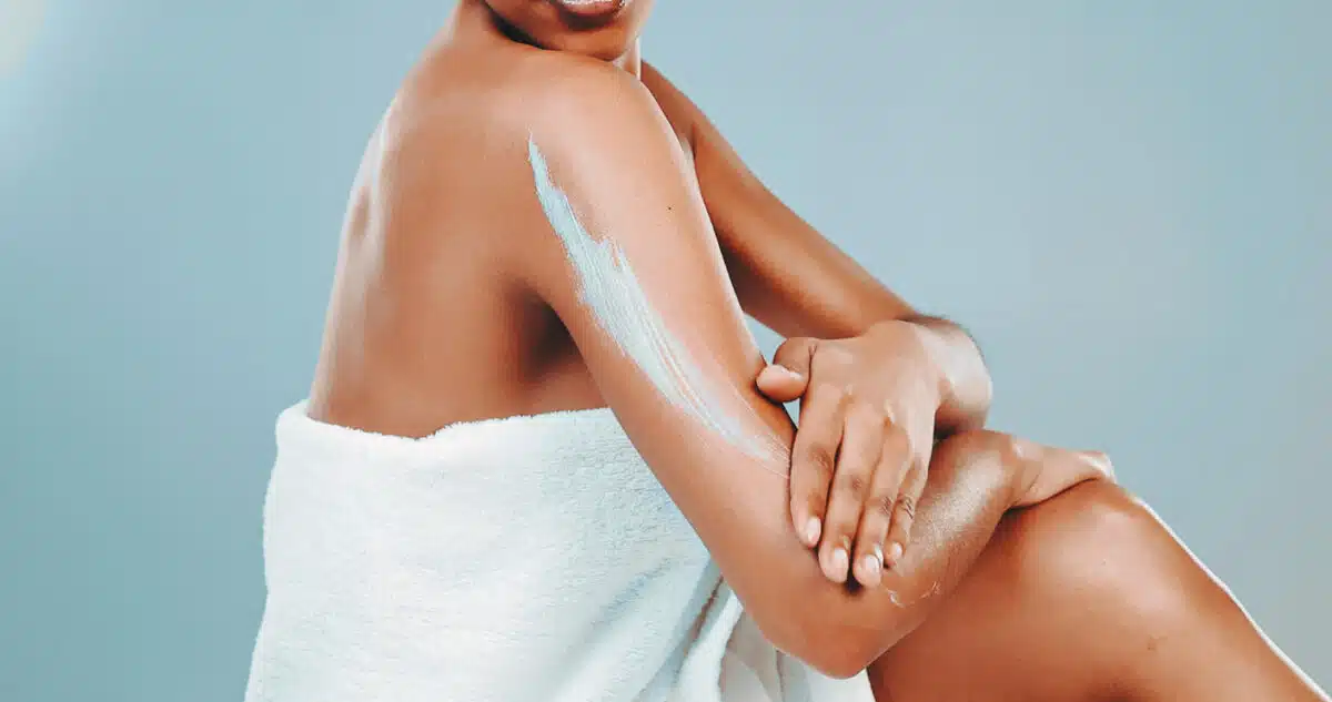 Woman putting on lotion after a shower