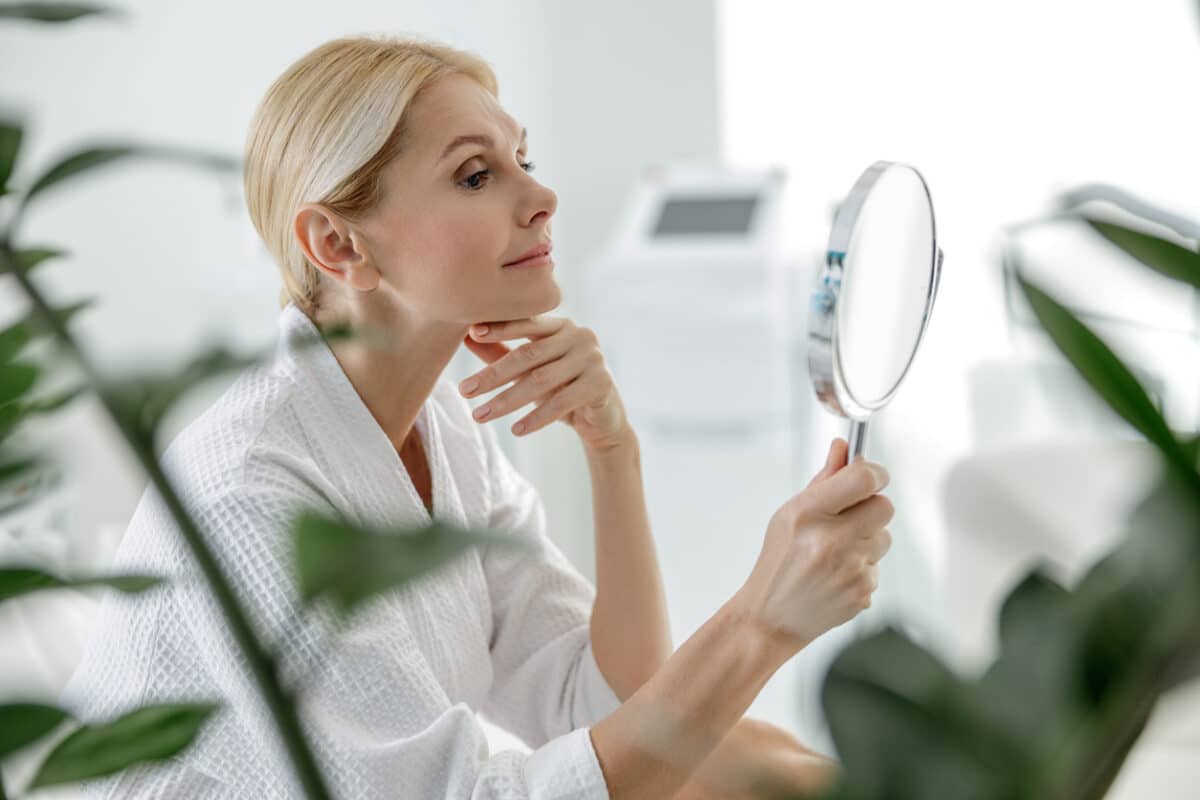 Woman looking in the mirror; beautiful skin; skincare