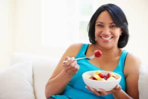 Woman eating a fruit bowl, pros and cons of eating the same thing every day
