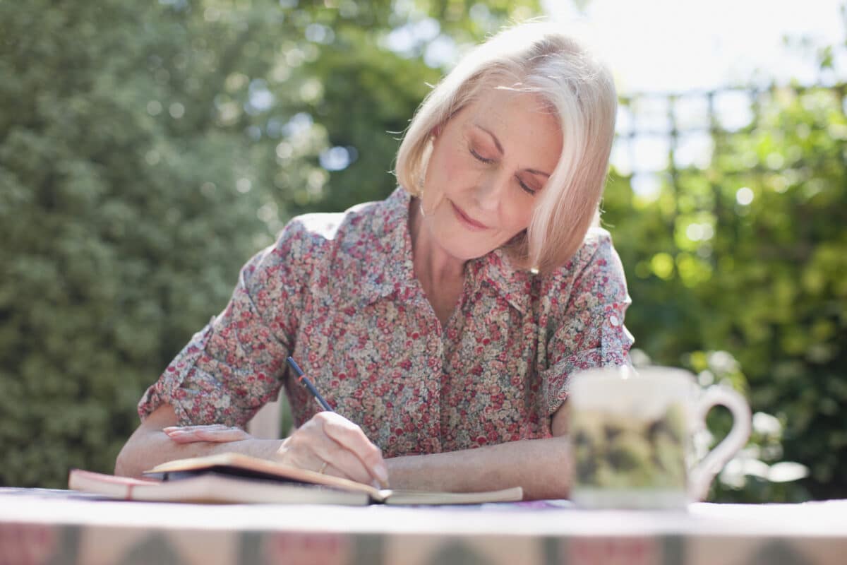 Woman writing in journal at patio table