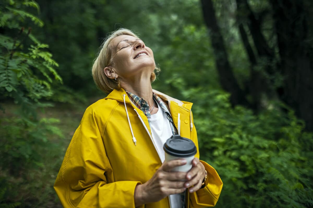 Female Hiker in a yellow raincoat exploring forest
