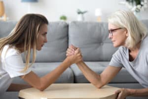 Mom and daughter arm wrestling; empowered aging