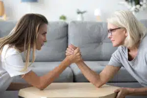 Mom and daughter arm wrestling; empowered aging