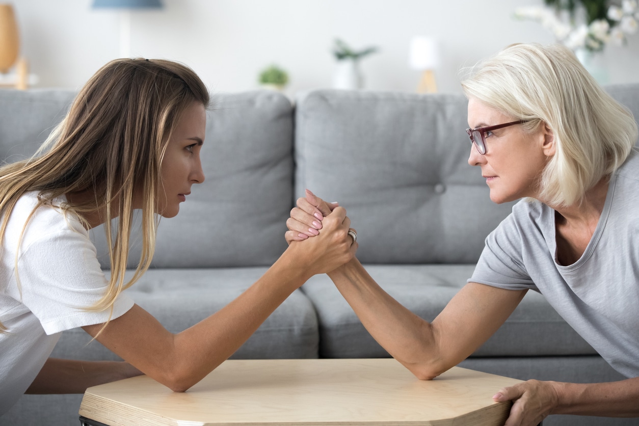 Mom and daughter arm wrestling; empowered aging