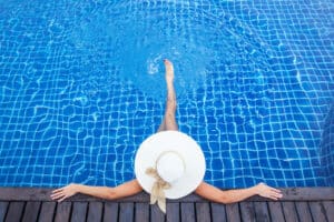 Woman sunbathing in a pool with a stylish sun hat