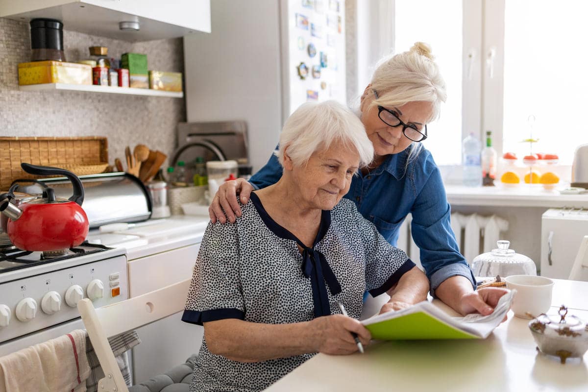 woman helping elderly mom with bills