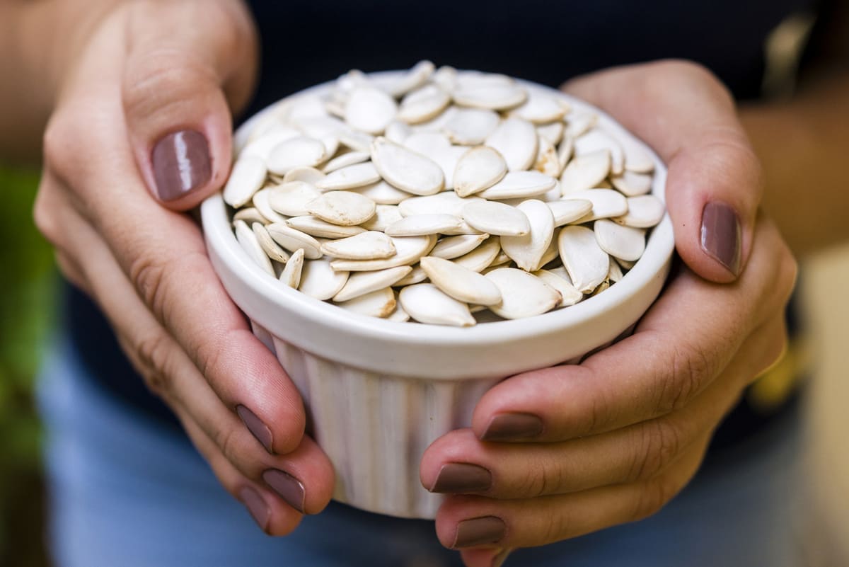 woman holding a bowl of pumpkin seed proteins