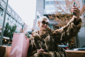 woman in a fur coat taking a selfie while out shopping
