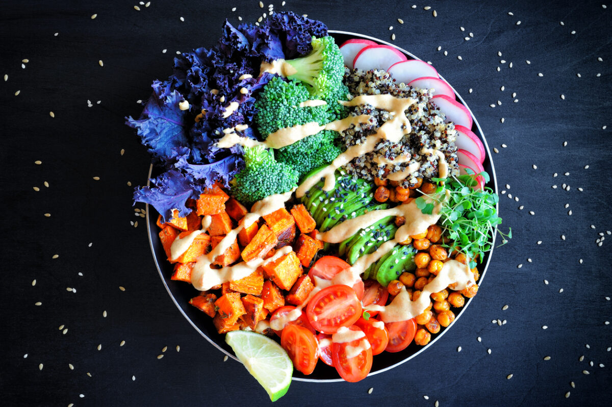 Vegan Buddha bowl with quinoa, baked sweet potato, red kale leaves, spicy chickpeas, avocado and micro greens.