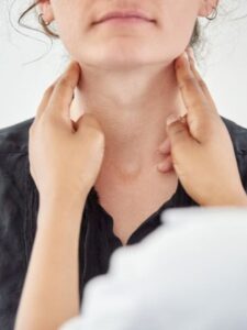 doctor checking womans throat or thyroid thyroid disorders FEATURE