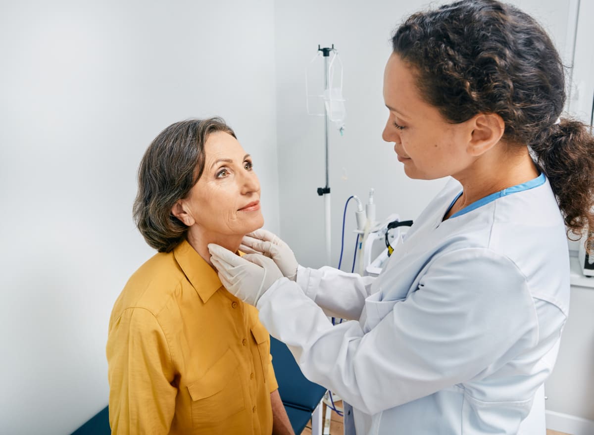doctor checking a womans thyroid
