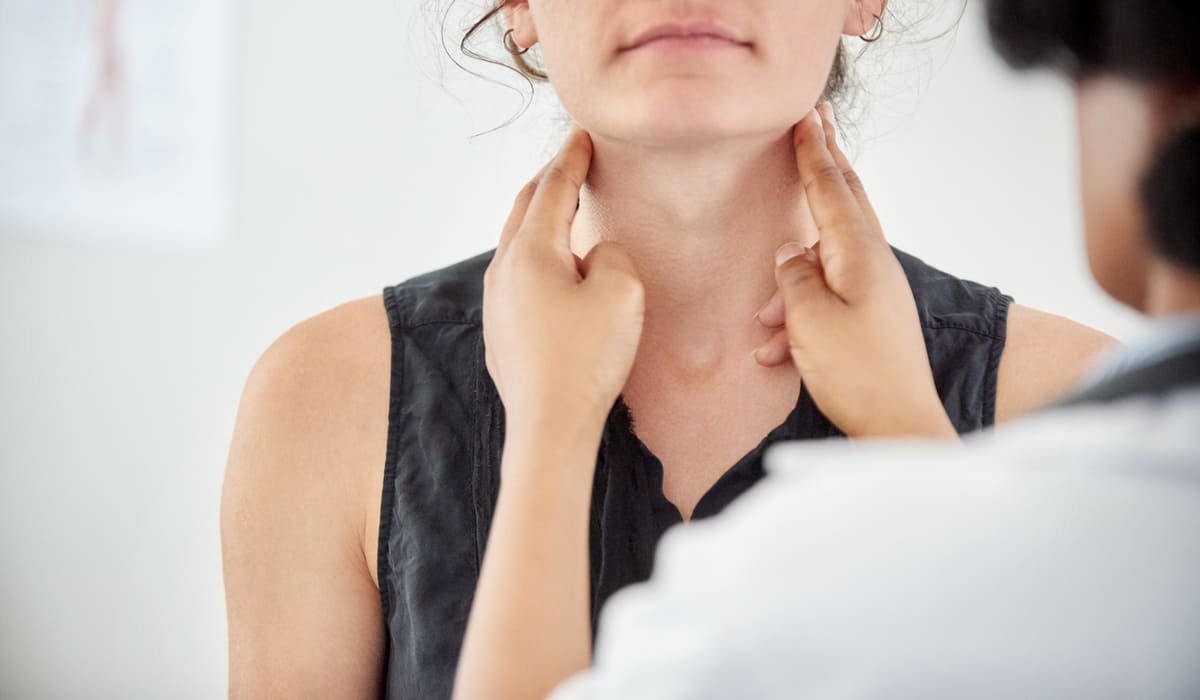 doctor checking womans throat or thyroid thyroid disorders FEATURE