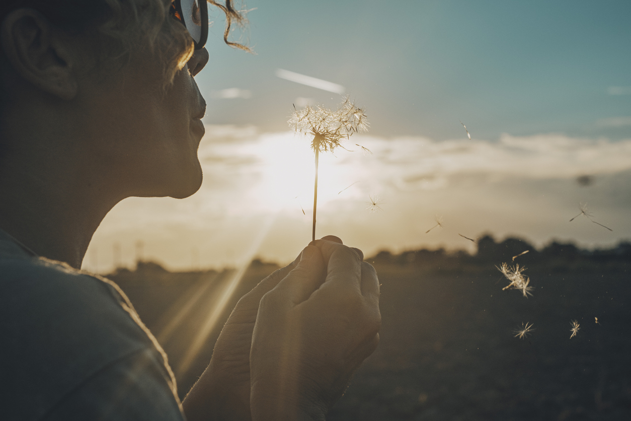 Self Journey, woman blowing on a dandelion, daydreaming and wishing