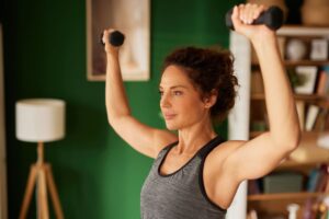 How to build lean muscle after 50, woman working out, dumbbell exercises