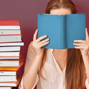 bookoutlet.com feature image, woman reading a book with a stack of books by her