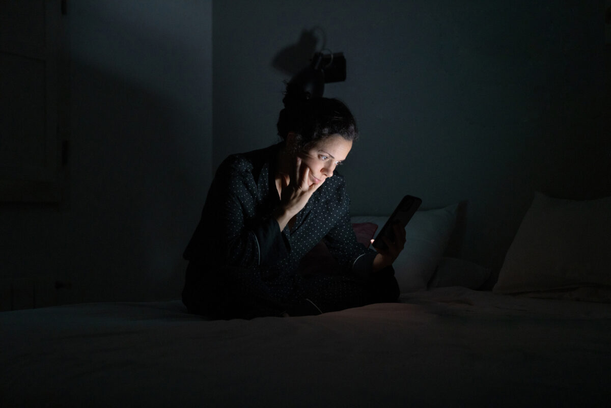 Woman using her smart phone late at night.