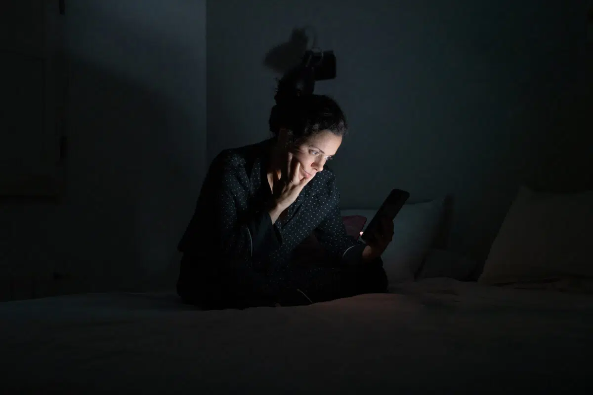 Woman using her smart phone late at night.