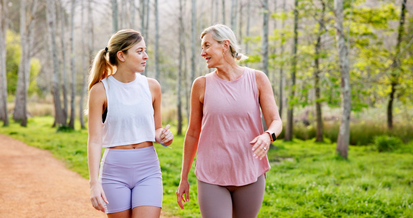 Active Rest -- Mother, daughter or talking in nature with hiking for fitness adventure, sightseeing or explore forest. Exercise, mature woman or girl in woods with walking, holiday travel or bonding on outdoor path