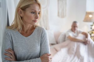 unhappy-woman-man-in-bed-in-background