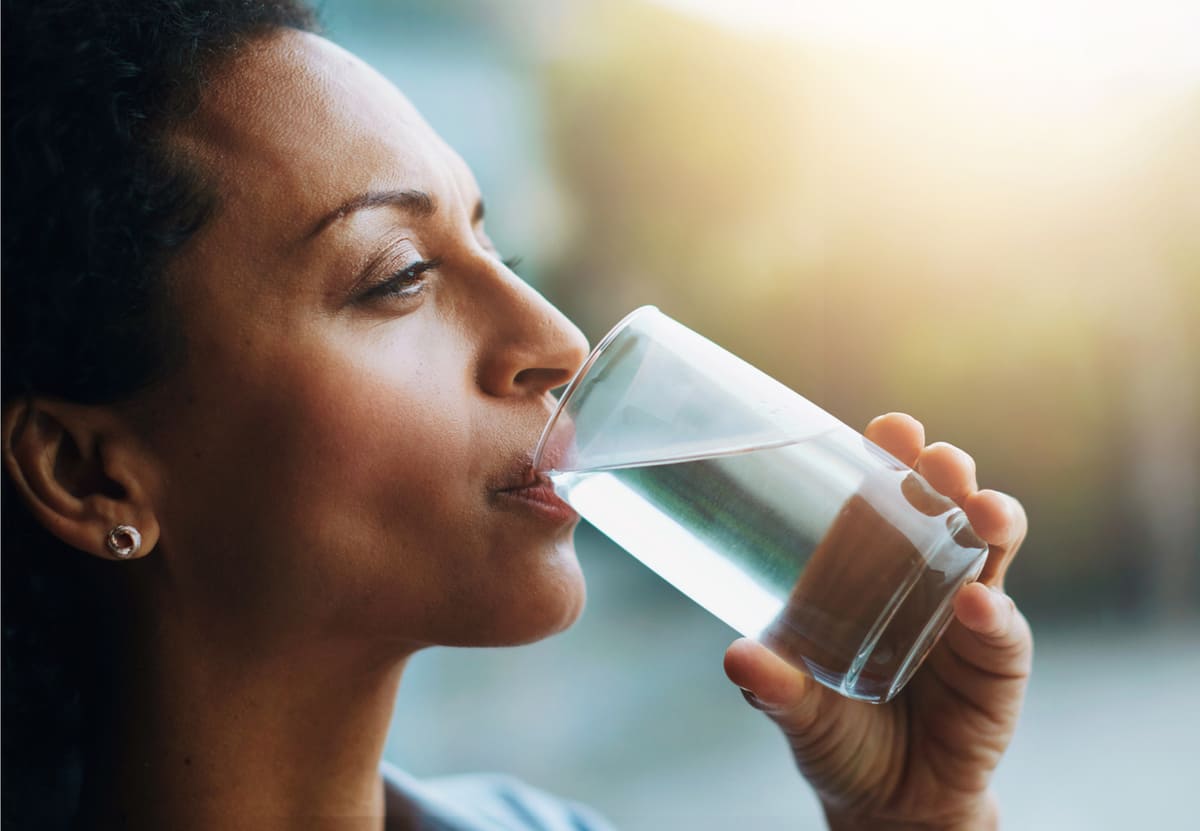 woman drinking glass of water for health