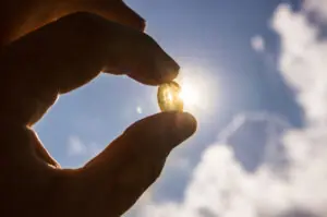 Vitamin D keeps you healthy while lack of sun. Yellow soft shell D-vitamin capsule against sun and blue sky on sunny day. Cure concept. Are You Getting Enough Vitamin D3 in Your Diet?