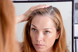 Woman looking at gray roots in the mirror