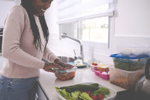 A young woman packing leftovers into a plastic container