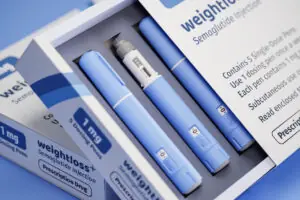Two packages of 5 dosing pens each of a fictitious Semiglutin drug used for weight loss (antidiabetic medication or anti-obesity medication) on a blue transparent background. Fictitious package design. The Truth About GLP-1 Medications the WHO