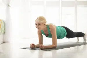 Home training concept. Smiling senior woman doing elbow plank in living room. 30 Days of Planking: The Surprising Brain Benefits of a Strong Core