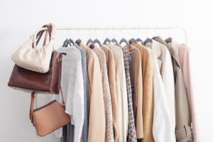 female autumn clothes on hangers in white room. Go-To Style Staples