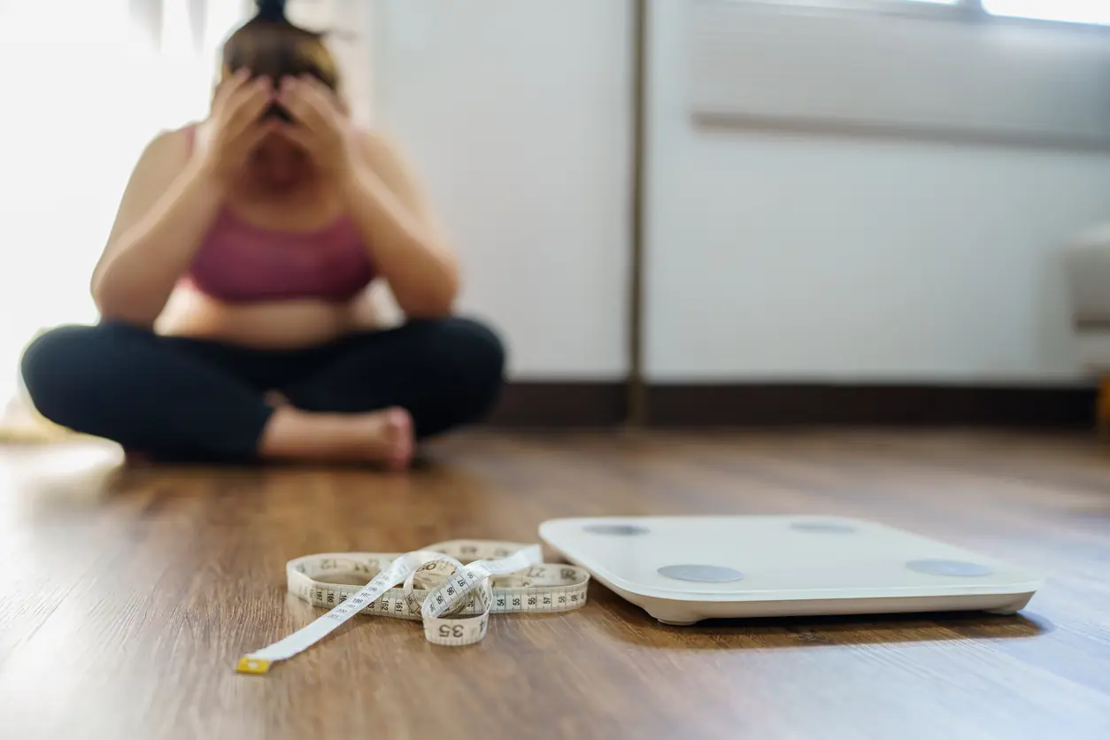 Obese Woman with fat upset bored of dieting Weight loss failÂ  Fat diet and scale sad asian woman on weight scale at home weight control. The Biggest Metabolism Mistake Women Over 50 Are Still Making