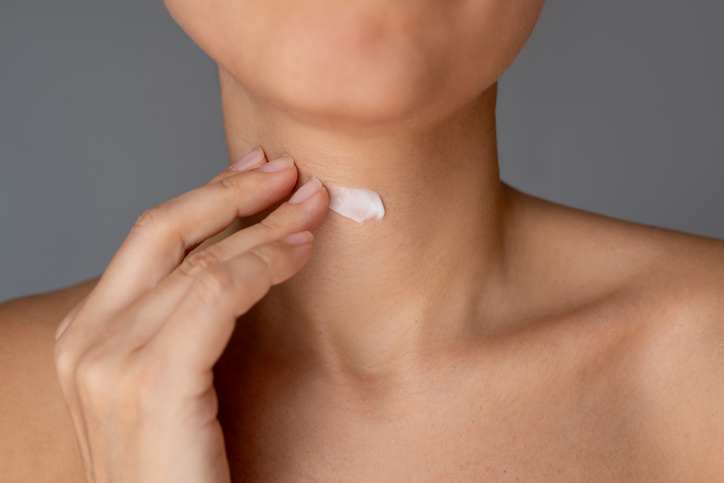 Young woman applying moisturizing cream on her neck. Anti aging skin care routine for neck wrinkles